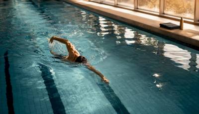 Person schwimmt entspannt eine Bahn im Schwimmbecken